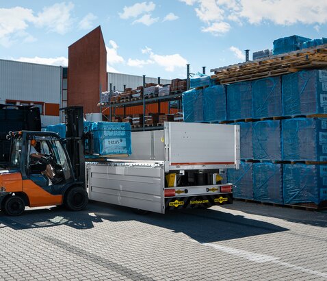 Vor einem Baumarkt werden mit einem Stapler Baustoffe in einen Anhänger verladen. | © Humbaur GmbH