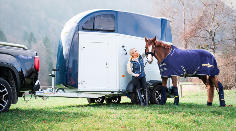 Eine Reiterin führt ihr Pferd in einen gelben Humbaur Pferdanhänger Modell Maximus. | © Humbaur GmbH