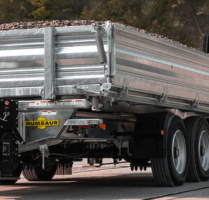 Een vrachtwagenaanhanger van Humbaur geladen met stenen wordt over een weg getrokken door een trekkend voertuig.  | © Humbaur GmbH